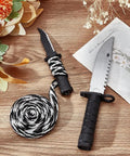 Decorative knife with black and white rope on a wooden surface, surrounded by flowers and a letter.