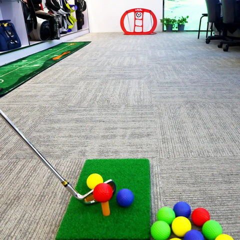 Indoor golf setup with Portable Indoor Golf Chipping Net With Hitting Mat For Backyard Practice and colorful foam balls on mat.