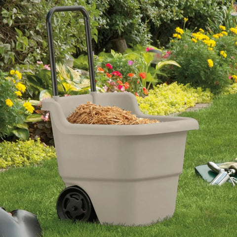 15 Gallon Resin Rolling Lawn And Utility Cart with retractable handle and 7 inch wheels, loaded with mulch in a garden setting