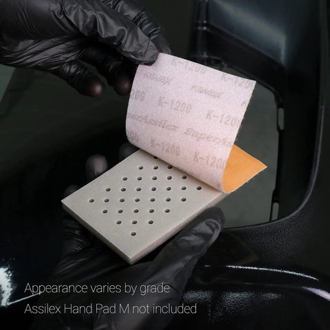 Flexible Sanding Sheets Peach K1500 Hook And Loop 25 Sheets Pack in use with Assilex Hand Pad, showing perforated design