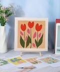 Four Sets Punch Needle Kit With 10x10 Frames For Beginners, floral pattern on display next to patterns, tools, and vase.