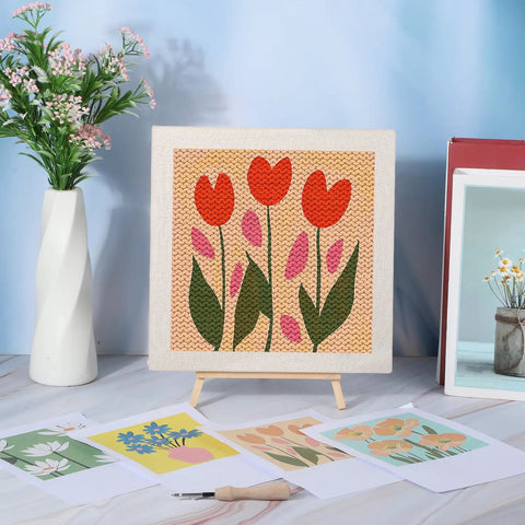 Four Sets Punch Needle Kit With 10x10 Frames For Beginners, floral pattern on display next to patterns, tools, and vase.