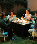 Friends gathered around a 42 Inch Propane Fire Pit Table With Ceramic Top 2 In 1 Fire Table Turns Any Patio Into A Cozy Lounge Black Outdoor Gas Firepit For Backyard Deck Or Patio Rectangular Shape, enjoying an evening outdoors.