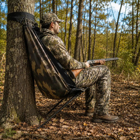 Hunter using low profile hunting chair hammock seat with 360 degree swivel, camouflage for deer and turkey hunts in forest