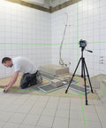 Boss Class 12V Max Three Plane Green Beam Laser Level in use, projecting green lines for precision in tile installation.