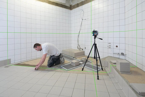Boss Class 12V Max Three Plane Green Beam Laser Level in use, projecting green lines for precision in tile installation.