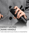 Person holding a Chestnut C3S Manual Coffee Grinder With All Metal Aluminum Body Conical Burr Hand Coffee Grinder Adjustable Grind Settings For On The Go Travel Camping And Home Black, focusing on crank handle.
