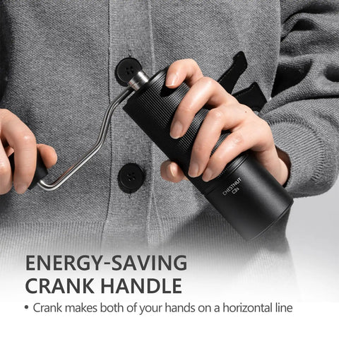 Person holding a Chestnut C3S Manual Coffee Grinder With All Metal Aluminum Body Conical Burr Hand Coffee Grinder Adjustable Grind Settings For On The Go Travel Camping And Home Black, focusing on crank handle.
