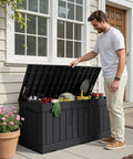 Man opening 78 Gallon Waterproof Resin Deck Box With Lockable Bench No Fuss Outdoor Storage For All Weather Patio Furniture Garden Tools And Pool Supplies Durable Black Resin With Rattan Pattern filled with tools and supplies on patio.