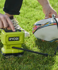 18V One Plus Cordless Tire And Ball Inflator With Mini Compressor 11 Bar Max Fast Inflation To 32 PSI In Under A Minute Includes 3 Tips Battery Not Included shown inflating a rugby ball on grass.