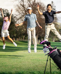 Three kids jumping with excitement near a Junior Golf Set For Kids 9-12 With Lightweight Graphite Shafts, Hybrid, Putter And Stand Bag