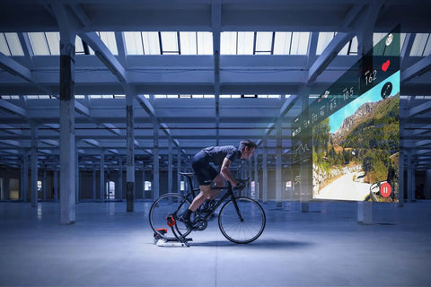 Cyclist using Fluid Resistance Bike Trainer With Quiet Indoor Ride, Immersed Flywheel for realistic outdoor feel in warehouse