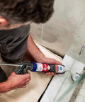 Person applying Supreme Silicone Caulk For Kitchen And Bathroom White 10 Ounce Cartridge 1 Pack on shower floor