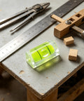 6Pcs Small Bubble Level 10x10x29mm Mini Square Spirit Level Picture on workspace with tools and wooden blocks.