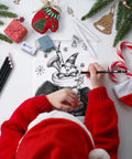 Person in red sweater drawing a Santa Claus sketch on white paper with pencils from a 22 Piece Sketching Pencil Set For Drawing With Graphite Pencils 12B To 2H Plus Black And White Charcoal Pencils Charcoal Sticks Blending Stumps Sharpener Kneaded Eraser And Vinyl Eraser Pro Grade For Artists And Students kit.