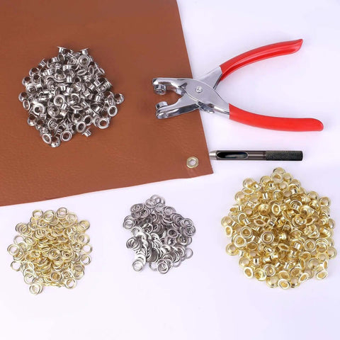 1203Pcs Grommet Eyelet Pliers Tool Kit With 1/4 Inch Eyelets And Washers, showing pliers on fabric with silver and gold eyelets