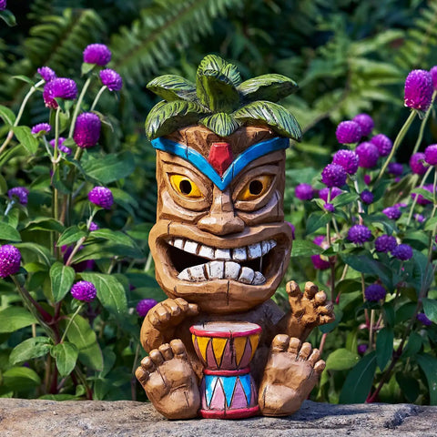 Colorful solar powered tiki statue light for garden, patio, and backyard decor, 10 inch tall, surrounded by purple flowers