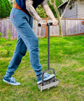 Person using Pre Assembled Manual Lawn Aerator With Three Stainless Steel Core Plugs And Soil Core Storage Tray on green lawn.