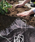 Heavy Duty 12 Inch Garden Stakes Pins Pro Grade 11 Gauge Galvanized Steel Landscape Staples being used for weed barrier fabric