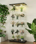 Five Shelf Glass Display Cabinet With Locking Door And Remote LED Lights in black finish showcasing flower collections in a room.
