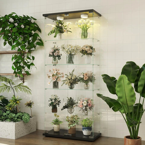 Five Shelf Glass Display Cabinet With Locking Door And Remote LED Lights in black finish showcasing flower collections in a room.