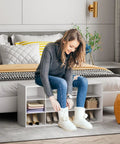Woman sitting on 12 Cubby Shoe Storage Bench With 3 Tier Vertical Wood Shoe Rack Organizer For Entryway Hallway Closet And Garage White Shoe Cabinet With Space Saving Design Durable And Easy To Clean, putting on slippers.