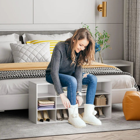 Woman sitting on 12 Cubby Shoe Storage Bench With 3 Tier Vertical Wood Shoe Rack Organizer For Entryway Hallway Closet And Garage White Shoe Cabinet With Space Saving Design Durable And Easy To Clean, putting on slippers.