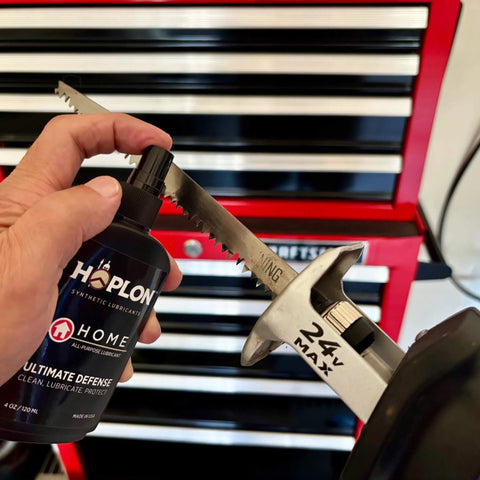 Hand holding All-In-One 5oz Synthetic Ester Lubricant Spray With Precision Needle next to saw blade in workshop