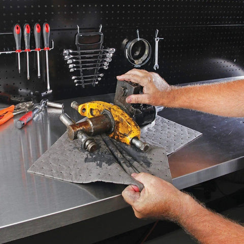 Premium Oil Absorbent Mat Pads 15 x 20 Inches used in workshop to clean oil from car parts on metal workbench
