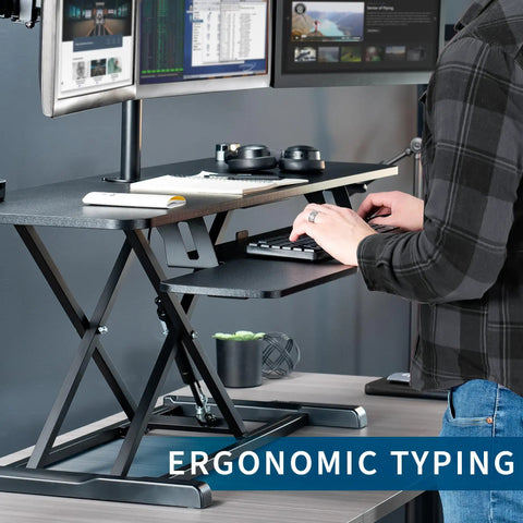 Height Adjustable 48 Inch Standing Desk Converter With Triple Monitor Mount for ergonomic typing setup in home office.