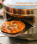 Pizza Oven Starter Bundle With Stainless Steel Outdoor Pizza Maker And Wood Fired Assembly, Pizza Stone, Thermometer, Peel, And Cutter For Backyard Pizza Nights And A Crust Twice As Crisp with pizza on peel