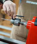 Person adjusting Heavy Duty Drill Chuck Set 5/8 Inch Capacity With JT33 MT2 And JT33 MT1 Taper Arbors on red lathe
