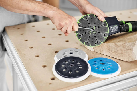 Person attaching ETS 150 Soft Sanding Pad For Heavy Duty Universal Use With High Temperature Durability StickFix Quick Change System