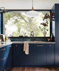 Modern kitchen with dark blue cabinets, pendant light, and large window. Includes matte black modern deck mounted kitchen soap dispenser.