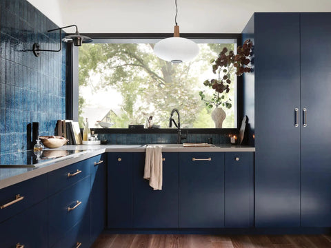 Modern kitchen with dark blue cabinets, pendant light, and large window. Includes matte black modern deck mounted kitchen soap dispenser.