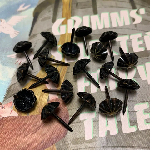 Premium 7/16 Inch Upholstery Tacks For Furniture Fix Ups, black decorative nailheads on a patterned surface.
