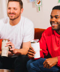 Two men enjoying drinks from 20oz Ceramic Lined Travel Tumblers With Double Wall Vacuum Insulation on a couch.