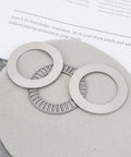 2 Pack Thrust Needle Roller Bearings with Washers NTA2031 on grey surface, adjacent machine components, 1.25 in bore, 1-15/16 in OD, metal construction