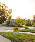 Double Sided Yard Sale Signs Kit 10 Pack Fully Assembled with Metal U Stake 22 by 14 Inches Bright Yellow Red Black High Visibility Made in USA Great for Curbside Garage Sale Setups shown on grassy curb.