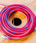 Coiled Beefy Built Tough Outdoor Extension Cord 50 Ft 12 Gauge 3 Conductor With Lighted End SJTW Contractor Grade on wooden surface.