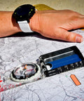 Advanced Mirror Compass For Pros And Serious Hikers With Metric UTM Scales displayed on a map with a hiker's hand