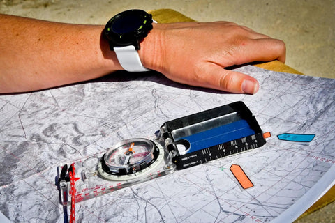 Advanced Mirror Compass For Pros And Serious Hikers With Metric UTM Scales displayed on a map with a hiker's hand