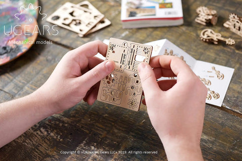 Hands holding Wooden Fidget Creations Set Four Mini Mechanical Puzzles You Build Without Glue Or Tools, stress relief wood puzzle kit
