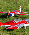 Two red RC airplanes on grass, illustrating vehicles using the RC Hobbyist Linkage Stoppers Set With Nuts And Screws For Servo Arms