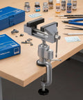 3 Inch Table Vise With Swivel And 360 Degree Tilt attached to a workbench, surrounded by model painting tools and supplies.