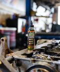 Adrenaline Assembly Lube 4 Oz bottle on engine block in garage setting, designed for gas and diesel engines with ultimate break-in protection.