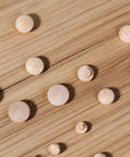Various sizes of smooth hardwood plugs laid on wooden surface, part of 120 Pieces Wood Plugs For Screw Holes In Furniture Cabinets And Tables