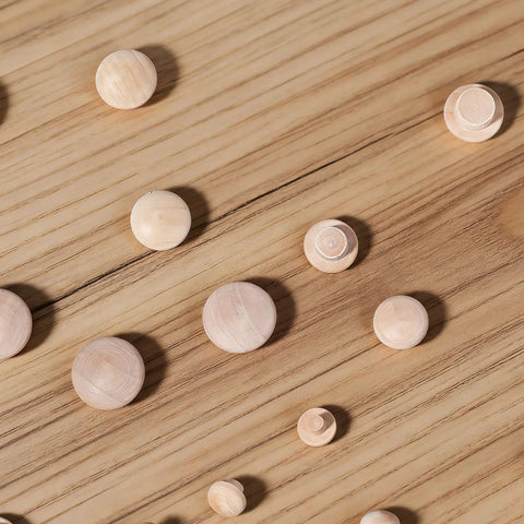 Various sizes of smooth hardwood plugs laid on wooden surface, part of 120 Pieces Wood Plugs For Screw Holes In Furniture Cabinets And Tables