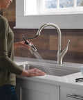 Modern Single Handle Kitchen Sink Faucet With Smooth As Silk Pull Down Sprayer In Grime Resistant Brushed Nickel featuring user operating sprayer.