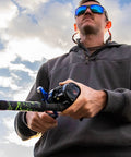 Angler holding Chaos XS Round Baitcasting Reel For Saltwater Inshore Surf Trolling And Catfish Beefy Yet Smooth Conventional Reel